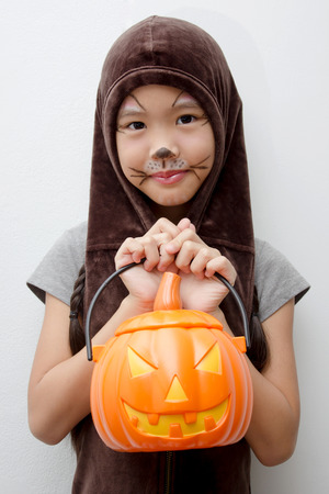 Portrait Asian girl with funny monster face holding pumpkin bucket and halloween costumeの写真素材