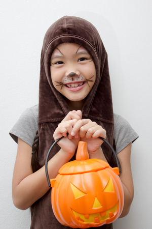 Portrait Asian girl with funny monster face holding pumpkin bucket and halloween costumeの写真素材