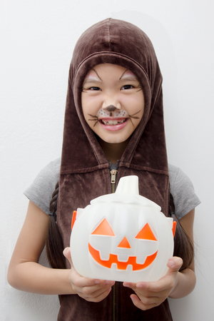 Portrait Asian girl with funny monster face holding pumpkin bucket and halloween costumeの写真素材