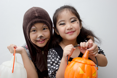 Portrait Asian girl with funny monster face holding pumpkin bucket and halloween costumeの写真素材