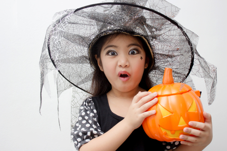 Portrait Asian girl on funny witch clothes holding pumpkin bucket and halloween costumeの写真素材