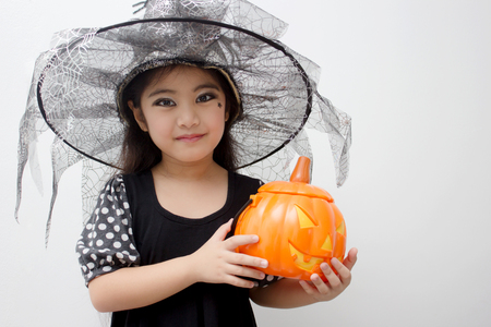 Portrait Asian girl on funny witch clothes holding pumpkin bucket and halloween costumeの写真素材
