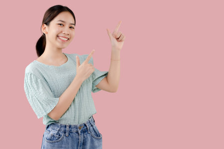 Young Asian lovely girl over isolated pink background pointing finger to the side with copy space.の写真素材
