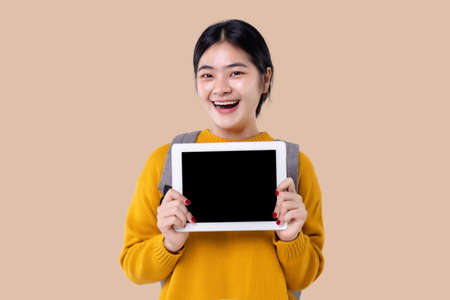 Young Asian student girl holding tablet computer with blank screen on isolated backgroundの写真素材