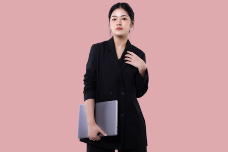 Young modern business asian woman holding laptop computer isolated over pink background.の写真素材