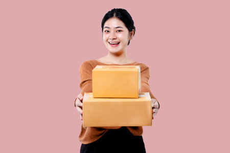 Happy Asian woman holding parcel box isolated over pink background.の写真素材