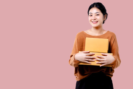 Happy Asian woman holding parcel box isolated over pink background.の写真素材