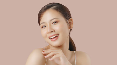 Close up portrait beauty shot of Beautiful Asian girl looking at camera isolated on brown background with copy space.の写真素材