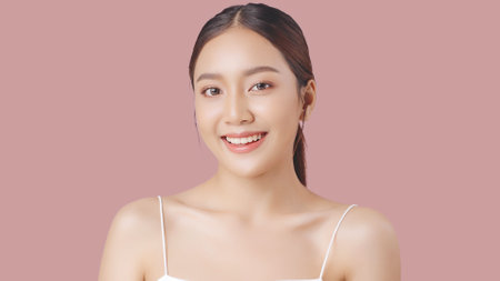 Close up portrait beauty shot of Beautiful Asian girl looking at camera isolated on pink background with copy space.の写真素材
