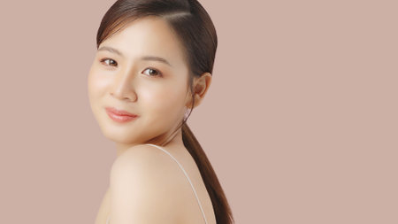 Close up portrait beauty shot of Beautiful Asian girl looking at camera isolated on brown background with copy space.の写真素材