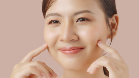Close up portrait beauty shot of Beautiful Asian girl looking at camera isolated on brown background with copy space.の写真素材
