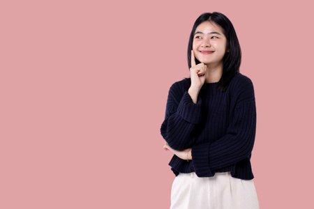 Beautiful young Asian girl thinking and looking upwards. The concept of content thinks isolated on pink background.の写真素材