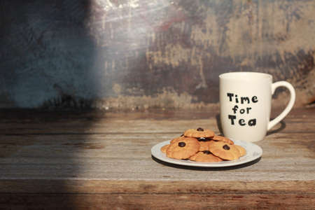 a cup of tea or coffee with chocolate cookies on the wooden chairの写真素材