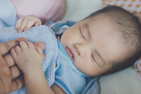 newborn baby concept : newborn cute Asian baby boy sleeping with blue blanket hand holding on mother hand : people and mother day conceptの写真素材