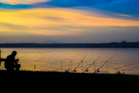 Men fishing and sunsetの写真素材