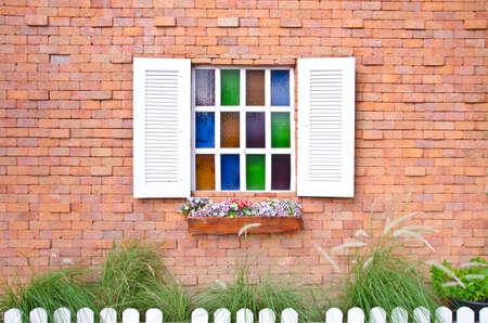 Vintage window with shutters that open and fresh flowers with colored glass and brick wallの写真素材