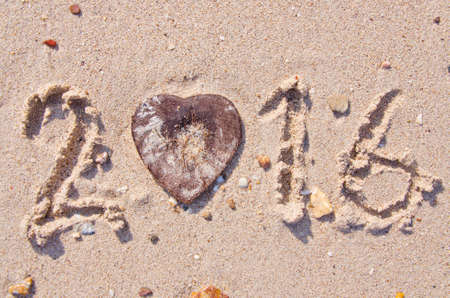 Happy New Year 2016 on the sand background Texture and Heart-shaped coconut shellの写真素材