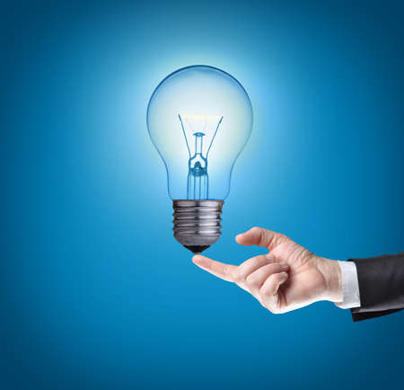 Light bulb on tip of finger on businessman Blue background  の写真素材