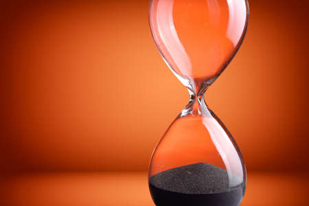 Closeup hourglass on orange backgroundの写真素材