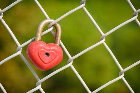 beautiful red heart-shaped padlock locked on iron chainの写真素材