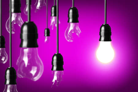 Idea concept with broken bulbs and one glowing bulbの写真素材