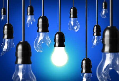 Idea concept with broken bulbs and one glowing bulbの写真素材