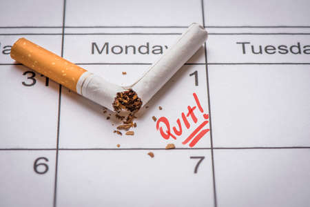 Broken cigarette on calendar. Time to quit smoking conceptの写真素材