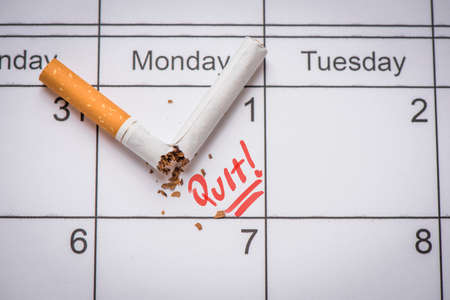 Broken cigarette on calendar. Time to quit smoking conceptの写真素材