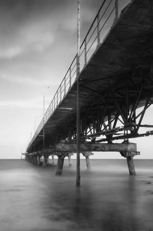 Black and white photo of old beach pier. Long exposure photographyの写真素材
