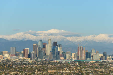 Downtown Los Angeles skyline with snow capped mountains behind at sunny dayの写真素材