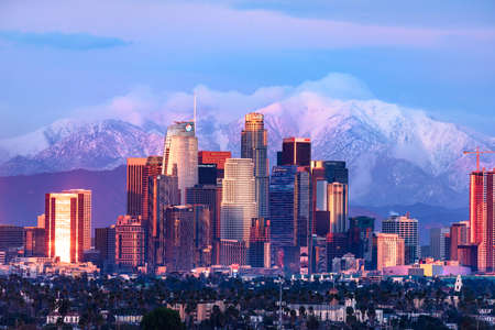Downtown Los Angeles skyline with snow capped mountains behind at sunsetのeditorial素材