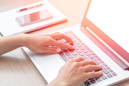 Close Up of woman hands using mobile phone and laptop computer business with blank copy space screen for your business advertising text message or content business in the morning light.の写真素材