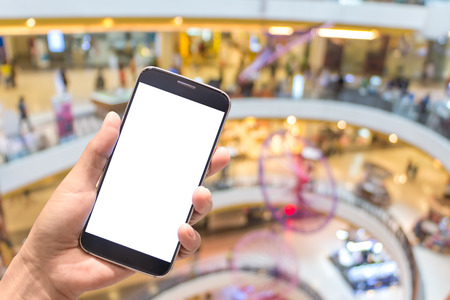 Asian women hand holding mobile phone screen blank background blur bokeh at a coffee shop in the department stores.の写真素材