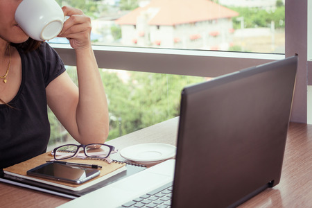 Close Up of woman hands using mobile phone and laptop computer with blank copy space screen for your advertising text message or content business in the Vintage effect.の写真素材