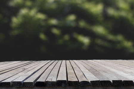 Empty old wooden table in front of blurred tree background in the forest. Can be used for display or montage for show your products.の写真素材
