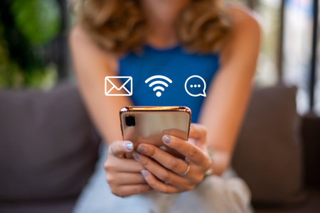 Multimedia and phone Applications Concept. young woman sitting on sofa using technology of digital gadget with modern graphic interface showing social, mailbox, wifi, messages icon on device.の写真素材