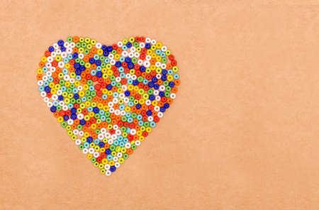 Colorful plastic beads  in heart shaped on a paper backgroundの写真素材