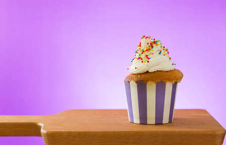 Cupcake against Purple background on wooden cutting boardの写真素材
