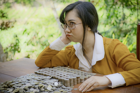 Business woman Hand Protecting With Stacked lots Coin, Portrait of beautiful tired young lady hands Pick up lots money on wooden table with white background, planning Investment and saving conceptの写真素材
