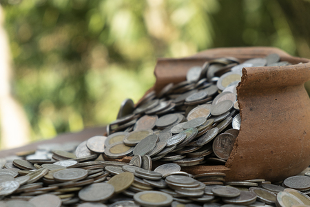 Coins in broken jar from on pile lots coin with blurred background, Money stack for business planning investment and saving conceptの写真素材