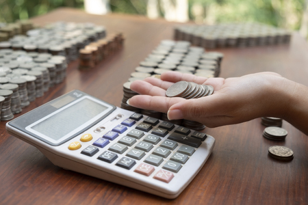Business woman counting lots stack coins on wooden desk background texture, Money for business planning investment and saving conceptの写真素材