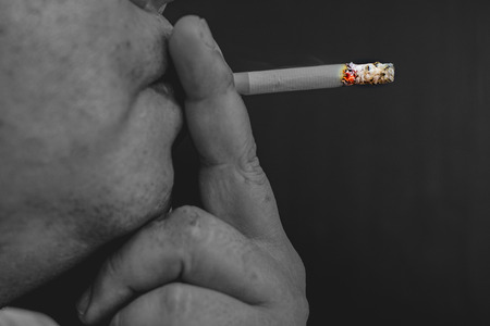 Man smoking a cigarette, Image of cigarette in hand with smokeの写真素材