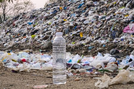 Plastic bottle on large garbage pile and pollution background