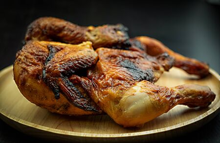 Roasted chicken on dish wood on black background