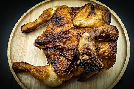 Roasted chicken on dish wood on black background