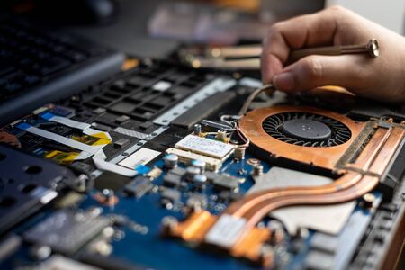 Technician repairing broken laptop notebook computer with screwdriver