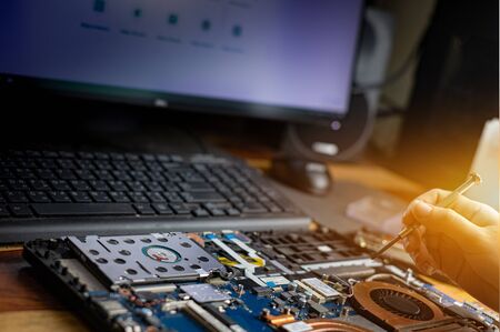 Technician repairing broken laptop notebook computer with screwdriver