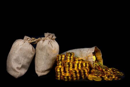 Lots of gold coin in treasure sack at black backgroundの写真素材