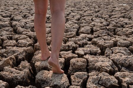 Women walking on cracked and dry soil in arid areas landscape, Drought crisis Conceptの写真素材