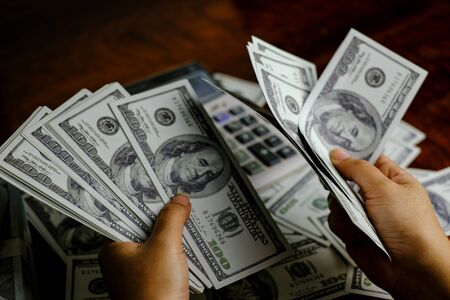Businessmen women counting money on a stack of 100 US dollars banknotes